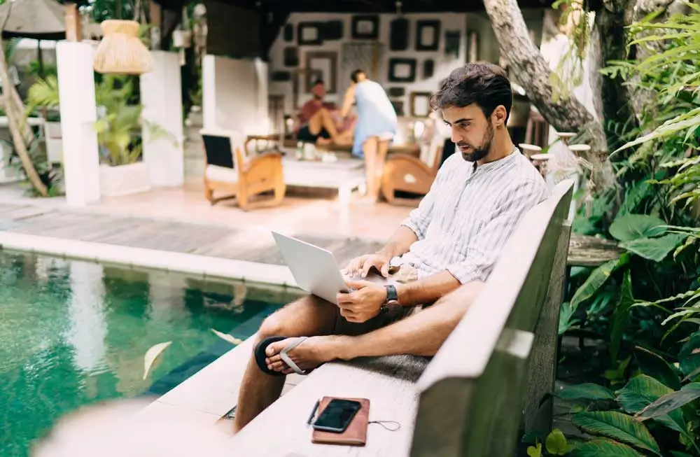 Freelancer working remotely on garage door marketing jobs from a tropical location near a pool
