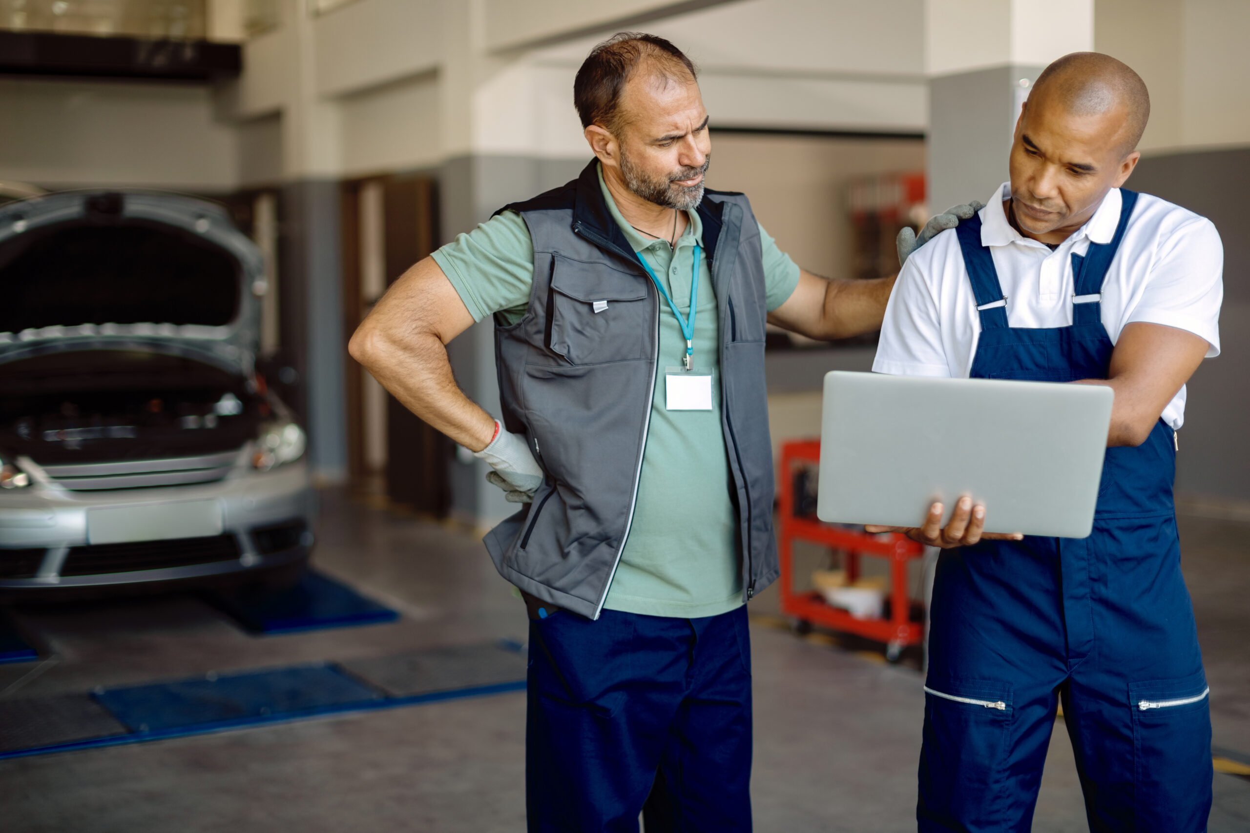 two coworkers using laptop while working at garage